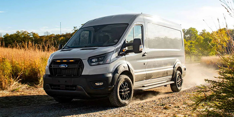 Grey Ford Transit van driving on dirt road